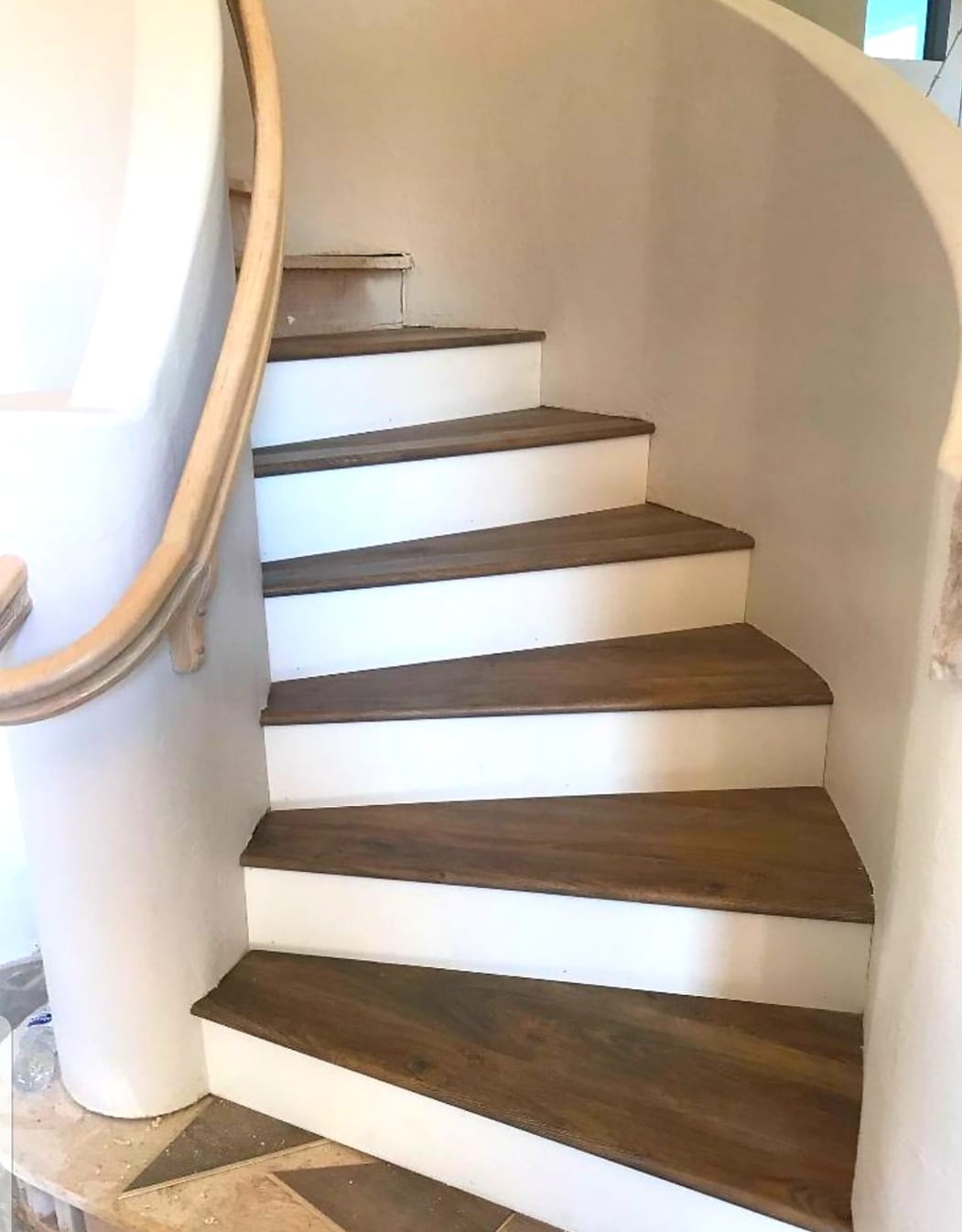 Dark wood accent flooring with white painted walls and light oak hand rail