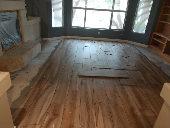 Livingroom floor with tile fire place in progress of having wood grain luxury flooring installed