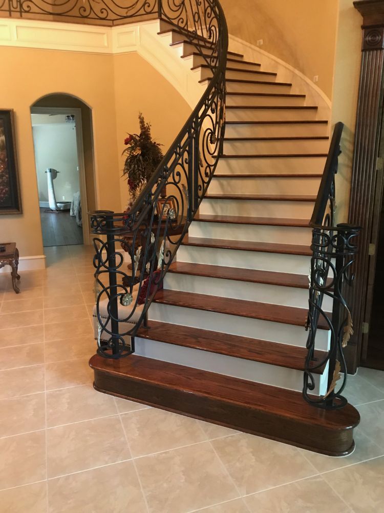 Dark brown wood floor with white paint accent color and spiraling iron banister detail
