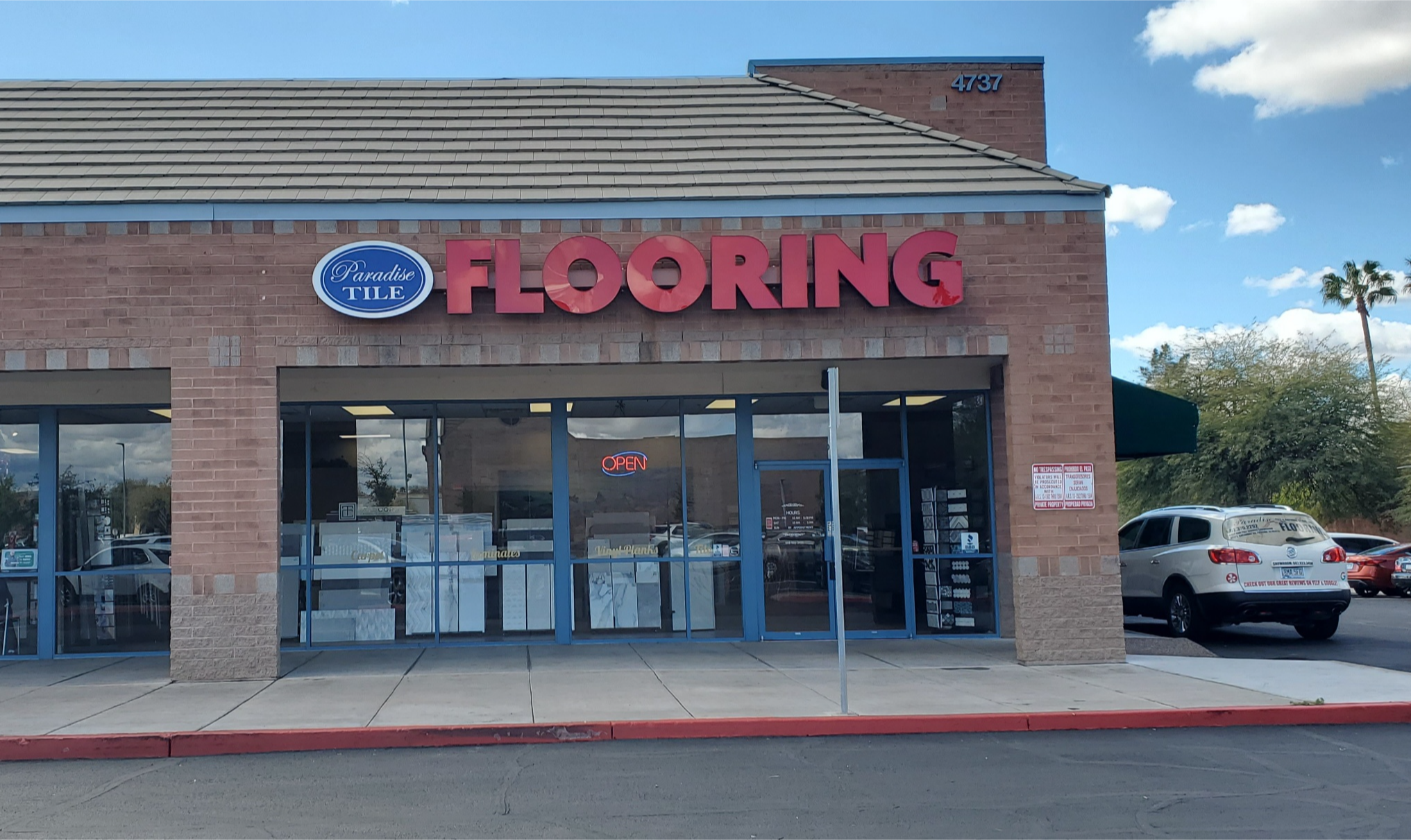 Paradise Tile and Natural Stone Flooring Showroom and Store Front with brick exterior and red Flooring sign