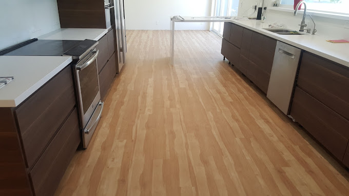 Light brown wood laminate flooring with dark brown cabinets and stainless steel appliances