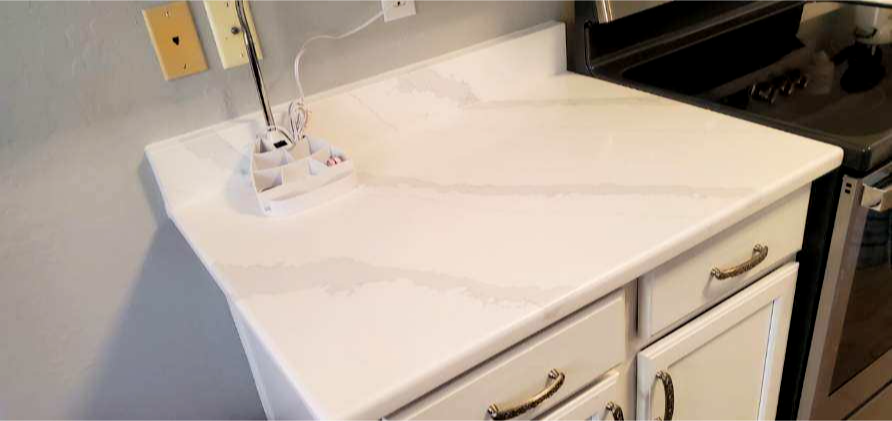 White quartz countertop with grey marble pattern in kitchen with white farmhouse cabinets